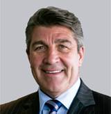 A person in a suit smiling
Description automatically generated