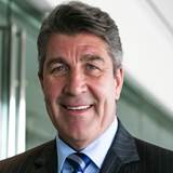 A person in a suit smiling
Description automatically generated